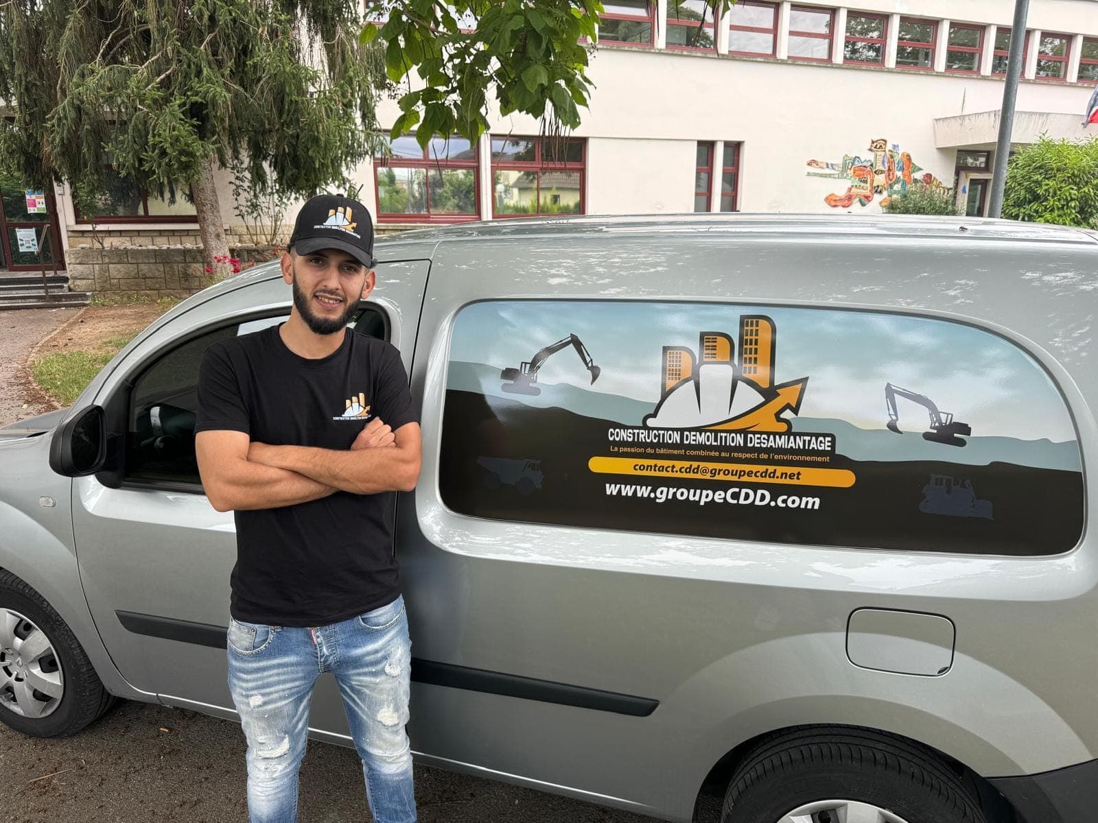 Compagnon CDD devant le véhicule utilitaire floqué aux couleurs de l'entreprise